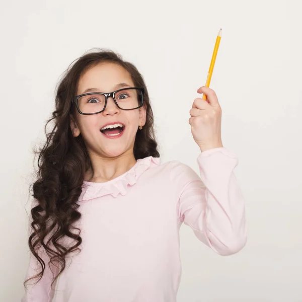 Ragazzina che solleva matita in gesto di attenzione divertente — Foto Stock