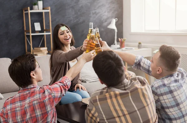 Happy young friends clinking beer bottles — Stock Photo, Image