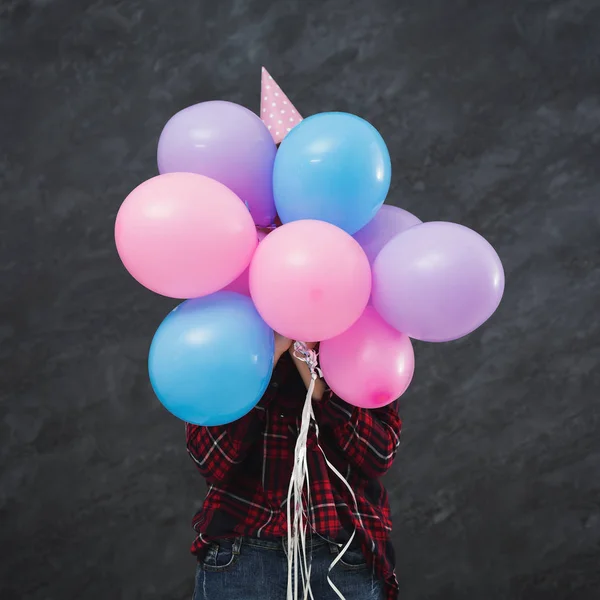 Chica en partido sombrero escondido detrás de globos — Foto de Stock