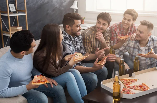 Jongeren in casual kleding eten pizza thuis — Stockfoto