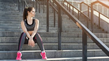 Genç kadın merdivenlerde rahatlatıcı yorgun