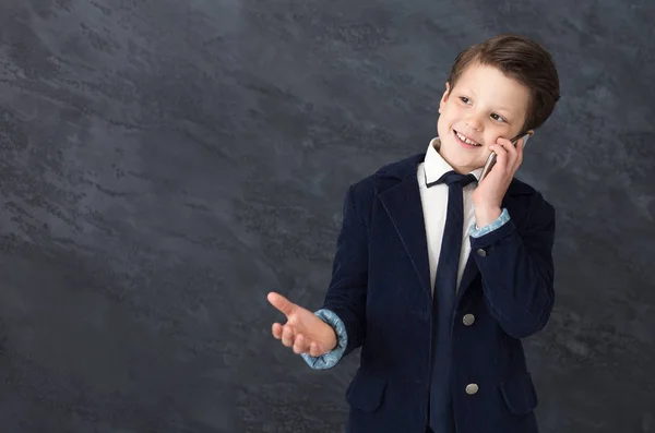 Маленький мальчик в костюме разговаривает по мобильному телефону — стоковое фото