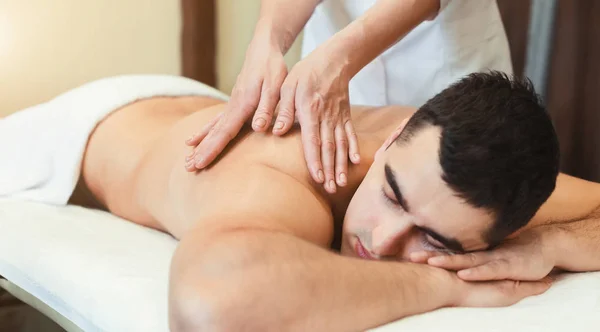 Porträt eines gutaussehenden Mannes, der Rückenmassage erhält — Stockfoto