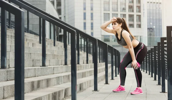 Exhausted athletic woman relaxing on stairs — Stock Photo, Image