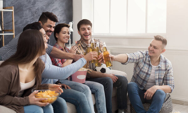 Happy young friends clinking beer bottles