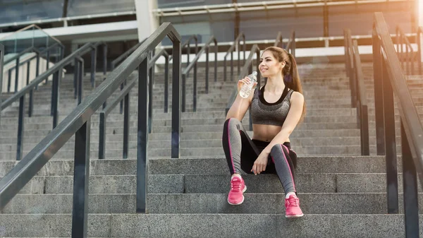 Happy young woman drinking water at stadium — Stock Photo, Image