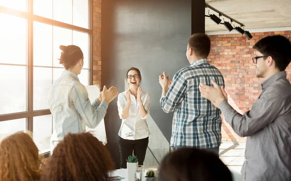 Young team clapping hands to colleague at meeting — Stock Photo, Image