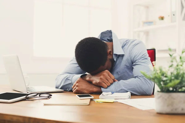 Sleeping overworking black businessman with laptop