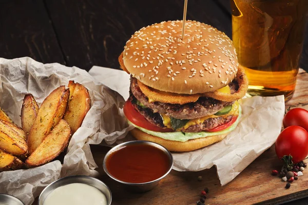 Burger and potatoes served with beer at restaurant, closeup — Stock Photo, Image
