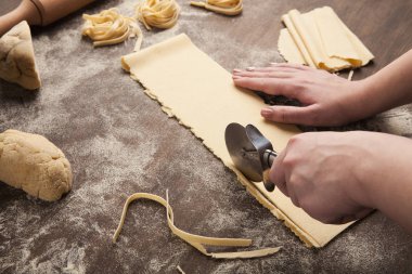 Chef using wheel cutter in preparation of pasta clipart