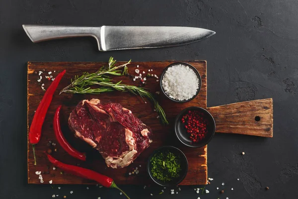 Rib eye steak with spices on wooden desk, closeup — Stock Photo, Image