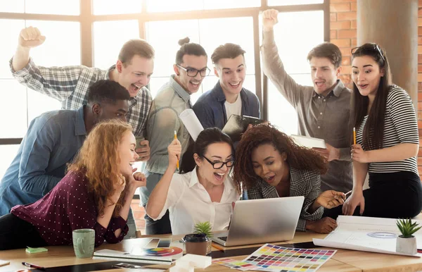 Equipo de jóvenes diseñadores disfrutando del éxito en la oficina —  Fotos de Stock