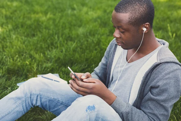 Student afro-american care ascultă muzică în parc în aer liber — Fotografie, imagine de stoc