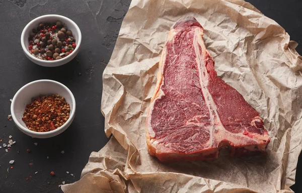 Raw t-bone steak on craft papper, dark background — Stock Photo, Image