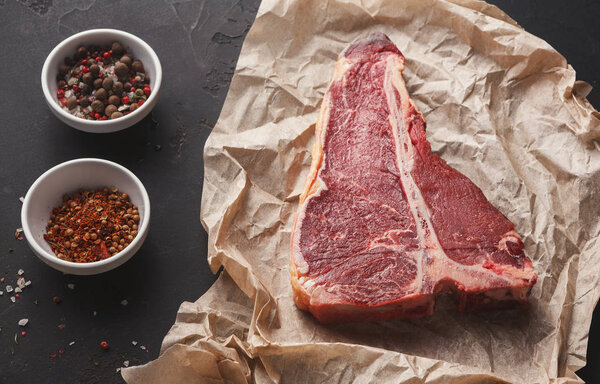 Raw t-bone steak on craft papper, dark background