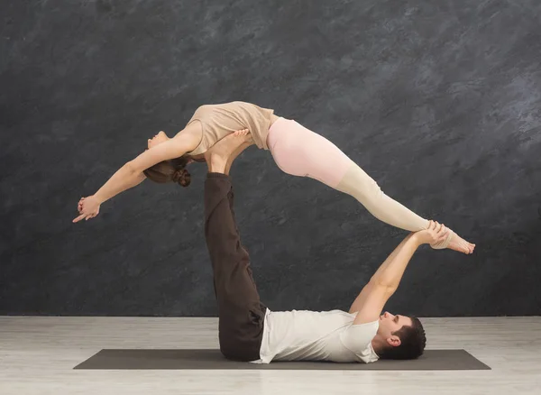 若いカップルが一緒にマットで acroyoga の練習 — ストック写真