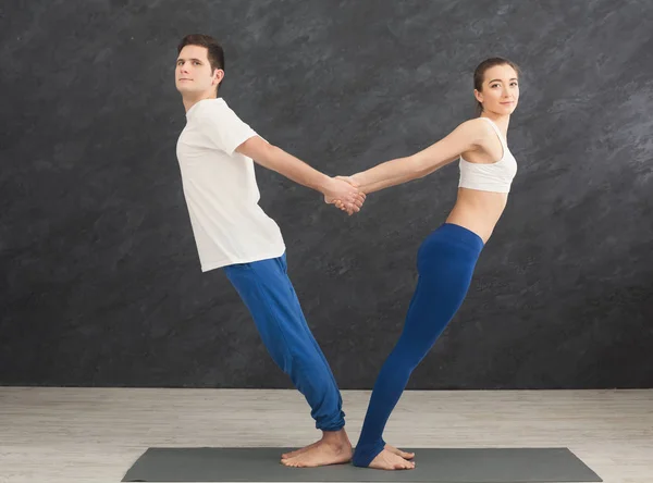 Couple training yoga in balance pose, back to back