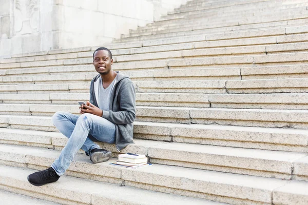 Açık havada Smartphone kullanarak mutlu Afrikalı-Amerikalı öğrenci