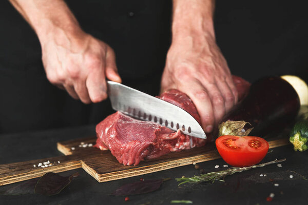 Chef cutting filet mignon on wooden board