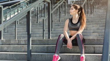 Merdivenlerde oturan yorgun genç kadın