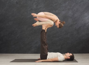 Genç çift acroyoga mat spor salonunda birlikte pratik. Kadın adam ayak çocuk poz, yan görünüm üzerinde Dengeleme. Ortak yoga, esneklik, güven kavramı, kopya alanı