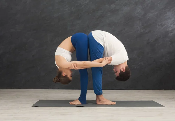 Junges Paar praktiziert gemeinsam Yoga im Fitnessstudio — Stockfoto