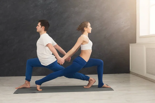 Couple training yoga in balance pose, back to back