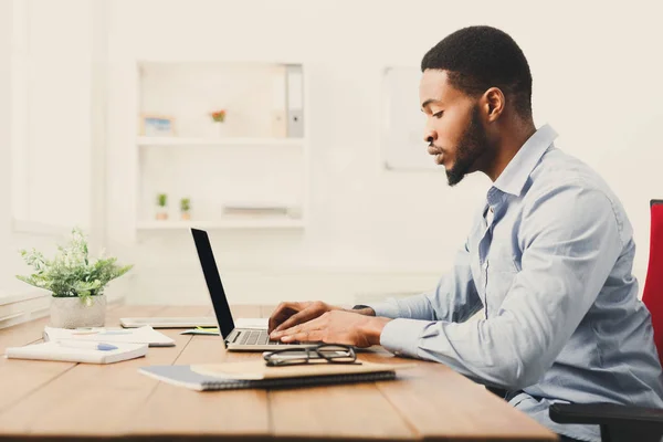 Ung svart affärsman arbetar med laptop — Stockfoto