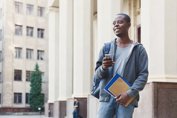 Feliz estudante afro-americano que envia mensagens no campus universitário — Fotografia de Stock