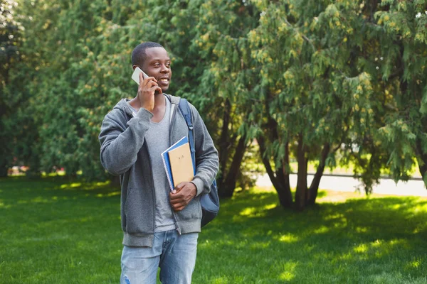 Feliz estudiante afroamericano hablando por teléfono inteligente en el parque — Foto de Stock