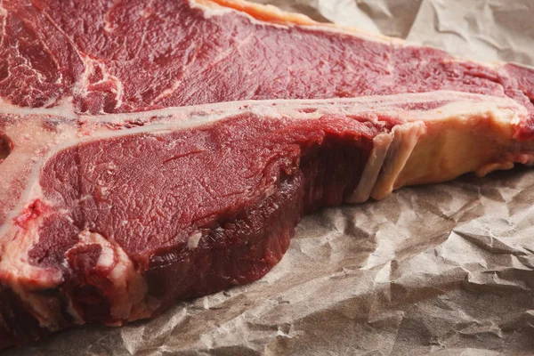 Bifteck cru au t-bone sur pappeur artisanal gros plan — Photo
