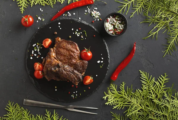 Rib eye steak on dark plate with thuja, top view — Stock Photo, Image