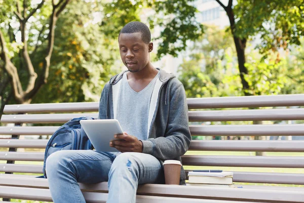 Серьезный африканско-американский студент с планшетом в парке на открытом воздухе — стоковое фото