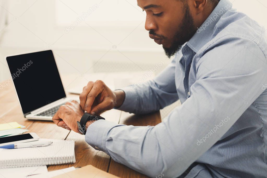 Young black businessman with smartwatch in office