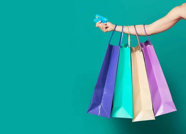 Mano femenina con tarjeta de cuna y bolsas de compras — Foto de Stock