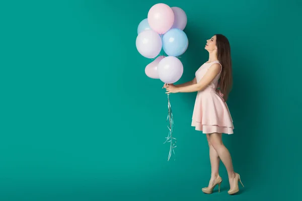 Glad tjej hålla ballonger över Blå studio bakgrund — Stockfoto