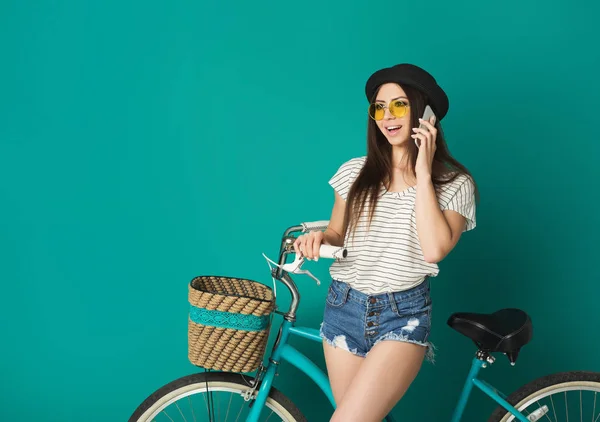 Happy girl posing with bicycle at blue studio background — Stock Photo, Image