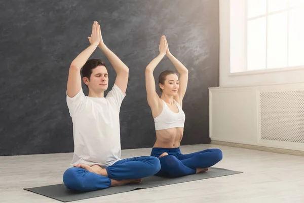 Pareja joven practicando yoga sentada en padmasana —  Fotos de Stock