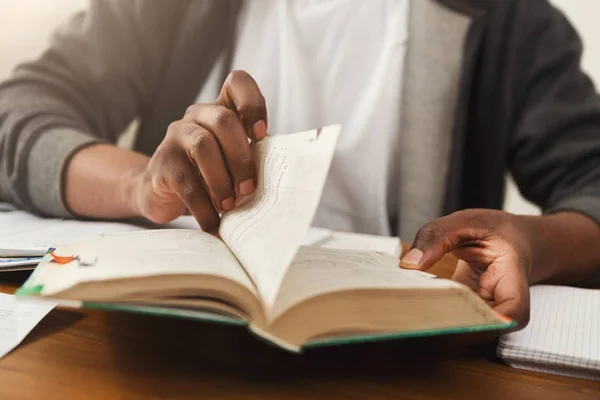 African-american man turning pages of book