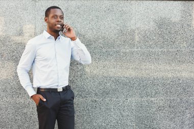 Cep telefonundan konuşurken kendine güvenen genç siyah işadamı portresi 