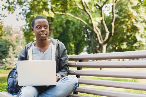 Jovem estudante afro-americano sorridente com laptop ao ar livre — Fotografia de Stock