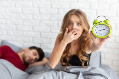 Geç işte. Şok kız yatakta çalar saat tutan