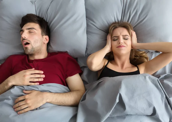 Snoring husband. Angry woman covering ears — Stock Photo, Image