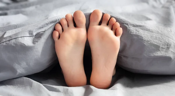 Piedi di giovane donna sdraiata a letto — Foto Stock