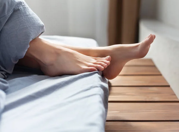 Sdraiato sul letto piedi femminili sotto coperta — Foto Stock