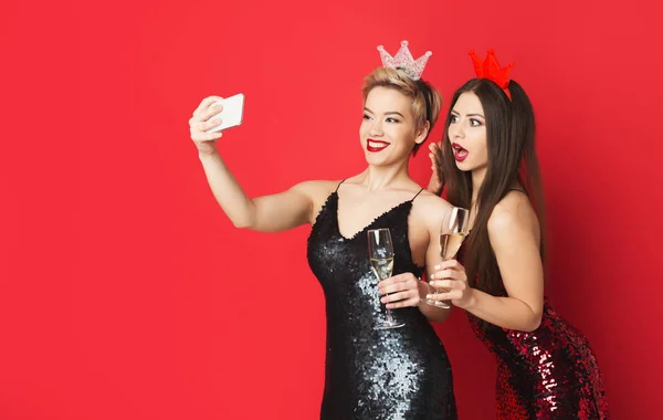 Chicas felices en vestidos de fiesta y tiaras haciendo vlog en el teléfono inteligente —  Fotos de Stock