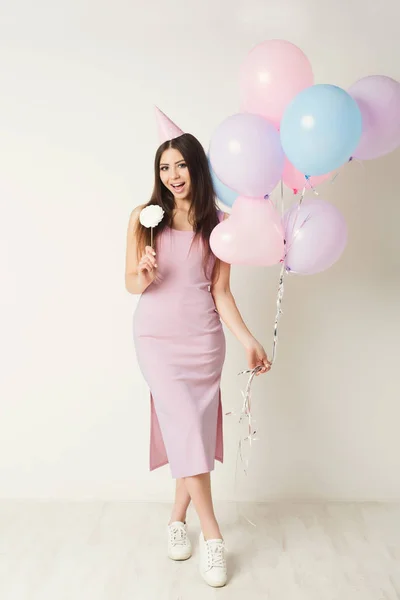 Birthday girl in party hat holding balloons — Stock Photo, Image