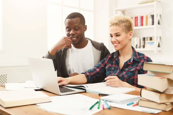 Estudantes do sexo masculino e feminino na mesa cheia de livros — Fotografia de Stock