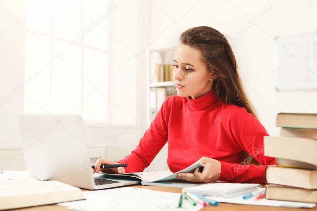 Student girl studying at table full of books