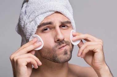 Yüz temizliğinde kafa havluya olan yakışıklı adam